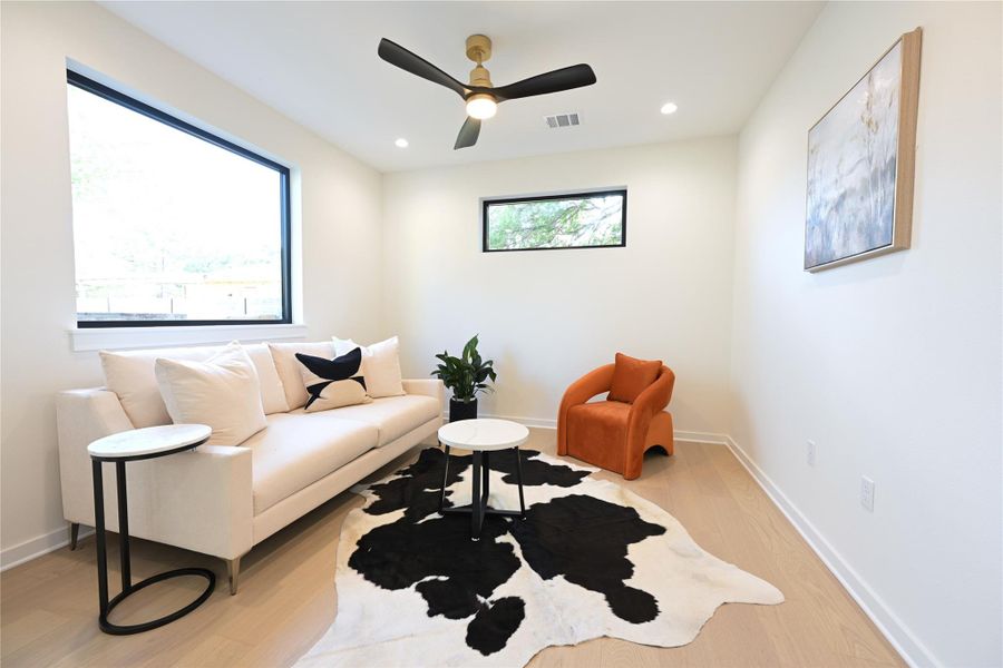 Bright room featuring large windows, light-colored flooring, and a ceiling fan with integrated lighting