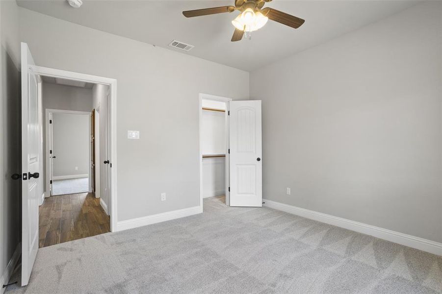 Unfurnished bedroom with carpet floors, ceiling fan, and a walk in closet