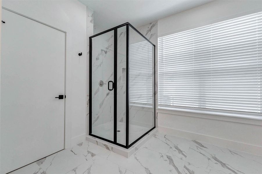 A striking glass-enclosed shower becomes the focal point of this bright bathroom, complemented by marble-inspired tile floors and coordinating shower surrounds. A large window fills the room with natural light, while bold black framing and streamlined hardware add a sophisticated contemporary finish. A striking glass-enclosed shower becomes the focal point of this bright bathroom, complemented by marble-inspired tile floors and coordinating shower surrounds. A large window fills the room with natural light, while bold black framing and streamlined hardware add a sophisticated contemporary finish.