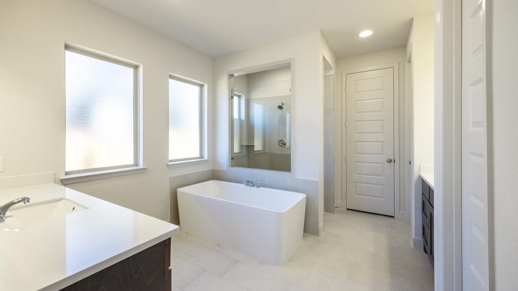 Full bathroom featuring recessed lighting, a freestanding tub, vanity, and a tile shower