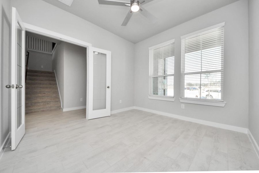 Experience the perfect blend of sophistication and warmth in this home office, boasting elegant wood-look tile flooring and flooded with natural light from expansive windows and French doors. Sample photo of completed home with similar floor plan. Actual colors and selections may vary. Experience the perfect blend of sophistication and warmth in this home office, boasting elegant wood-look tile flooring and flooded with natural light from expansive windows and French doors. Sample photo of completed home with similar floor plan. Actual colors and selections may vary.