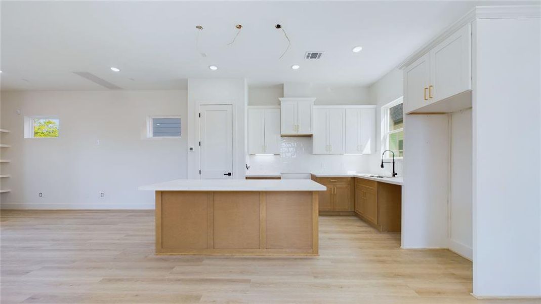 The kitchen features a large breakfast bar with seating for three, ample storage, and stylish pendant lighting (to be installed) for a touch of elegance.