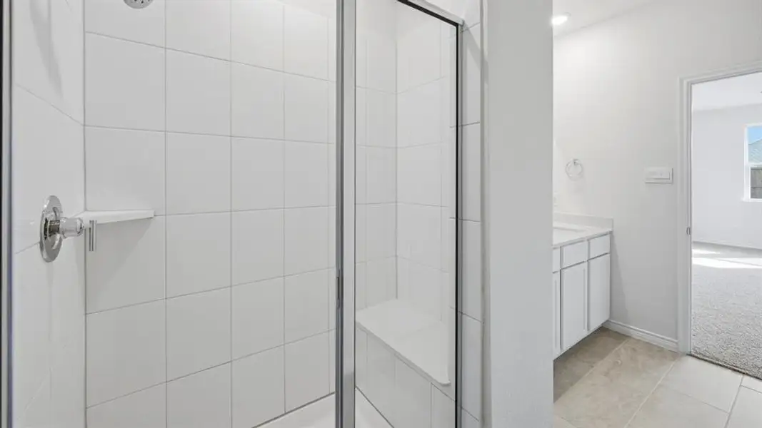 Spacious shower enclosure with clear glass panel, featuring white subway tile surround and a built-in shower bench Spacious shower enclosure with clear glass panel, featuring white subway tile surround and a built-in shower bench