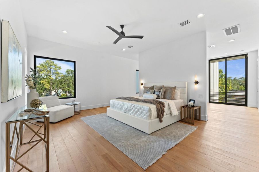 Bright and spacious bedroom with modern decor, featuring large windows, a comfortable bed, and sleek furnishings. Hardwood floors and neutral tones create a warm, inviting atmosphere. Ample natural light and outdoor views enhance the space's appeal.