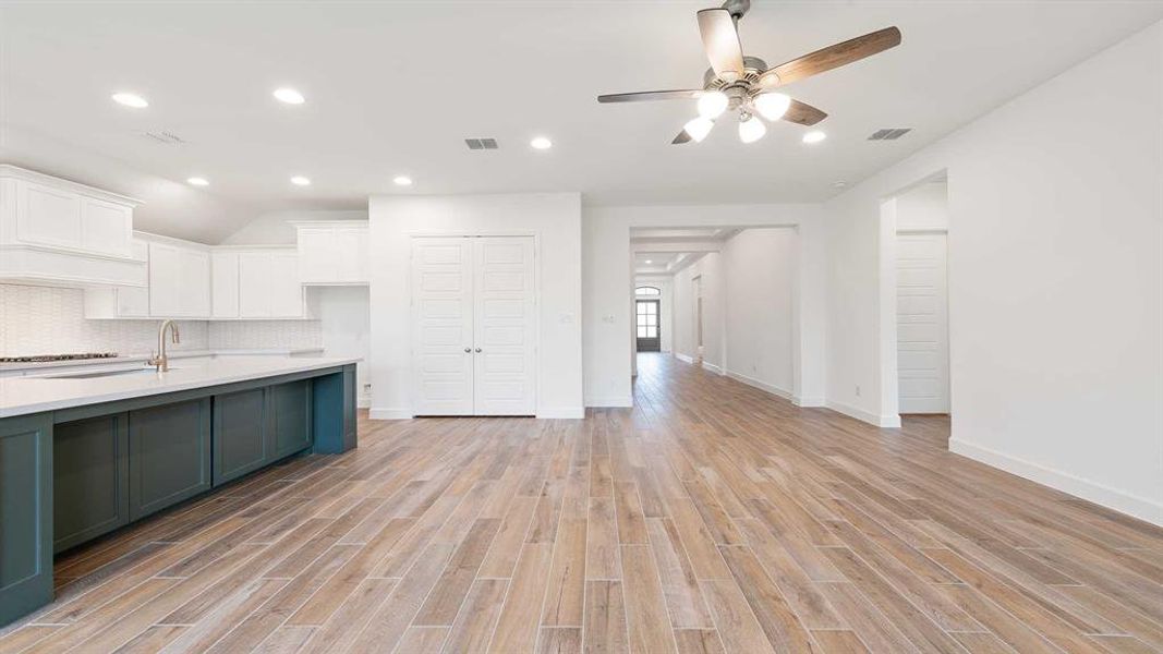 Kitchen featuring decorative backsplash, white cabinets, light hardwood / wood-style floors, and ceiling fan