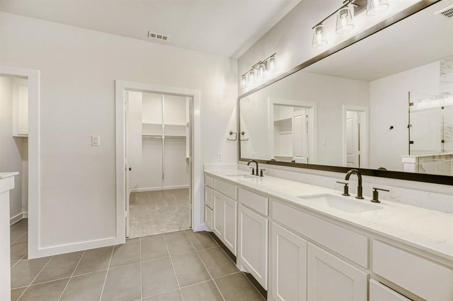 Bathroom with double vanity, a spacious closet, light tile patterned flooring, and a shower with door