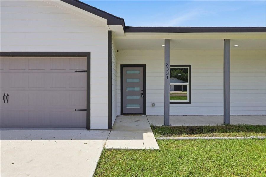 A covered front porch with contemporary support pillars welcomes guests to the front door. A covered front porch with contemporary support pillars welcomes guests to the front door.