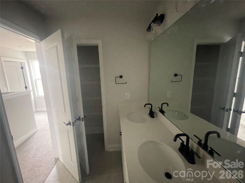 The secondary upstairs hall bathroom also has dual sinks and linen closet
