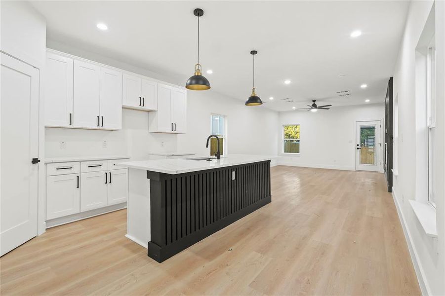 Kitchen with recessed lighting, white cabinets, an island with sink, hanging light fixtures, and light wood-style flooring Kitchen with recessed lighting, white cabinets, an island with sink, hanging light fixtures, and light wood-style flooring