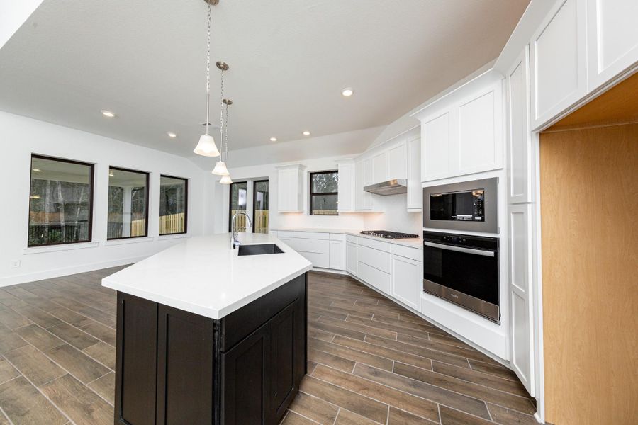 The stunning and generously sized center island features a breakfast bar, perfect for casual dining and entertaining. The island is beautifully designed with pristine quartz countertop and elegant pendant lights.