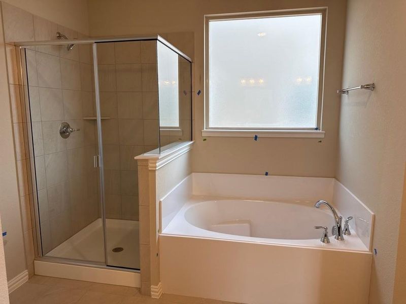 Bathroom featuring a built-in soaking tub with chrome fixtures, a frosted window, and a glass-enclosed shower with tile surround