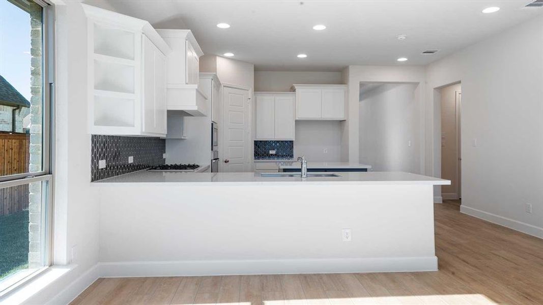 Kitchen featuring backsplash, light hardwood / wood-style floors, white cabinetry, and sink