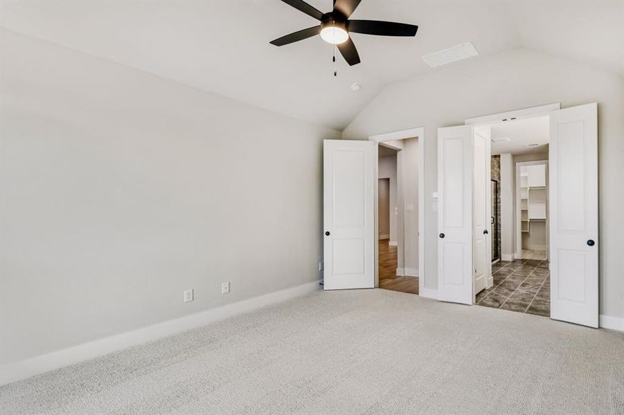 Unfurnished bedroom featuring a spacious closet, carpet floors, and ceiling fan