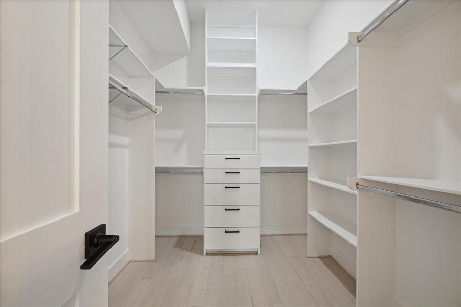 This extra large walk-in closet is off the primary bathroom with custom built-in shelves and drawers for jewelry, linens, and much more!