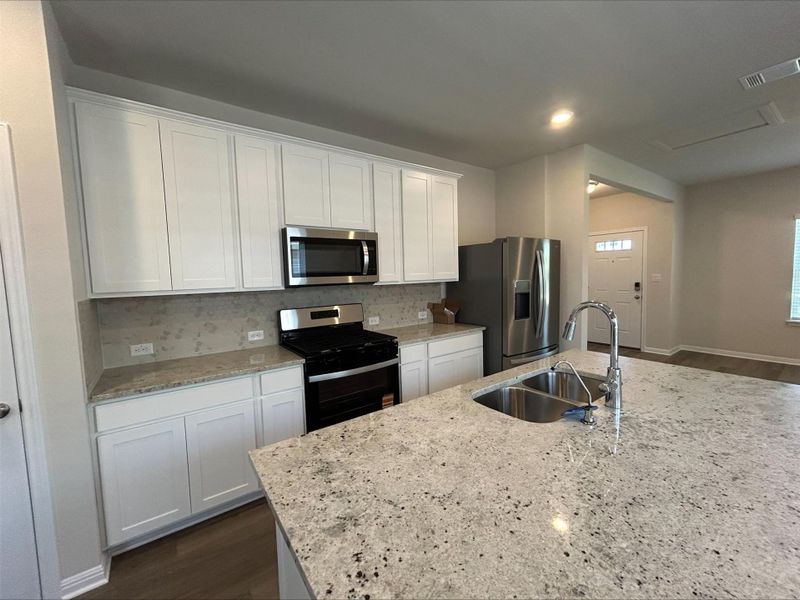 Kitchen with stainless steel appliances, white cabinets, backsplash, dark wood finished floors, and recessed lighting Kitchen with stainless steel appliances, white cabinets, backsplash, dark wood finished floors, and recessed lighting