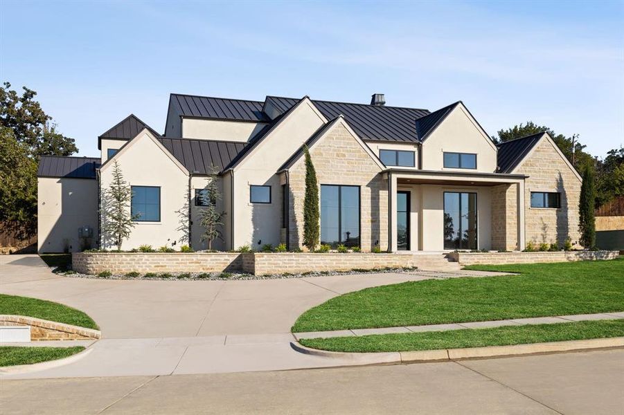Modern farmhouse featuring a standing seam roof, a metal roof, stone siding, and stucco siding Modern farmhouse featuring a standing seam roof, a metal roof, stone siding, and stucco siding