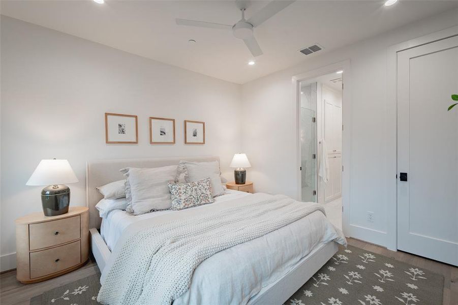 Bedroom with ensuite bathroom, dark hardwood / wood-style floors, and ceiling fan