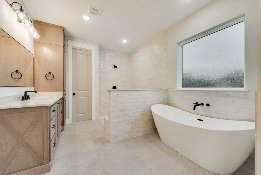 Bathroom featuring vanity, a bath, tile walls, and tile patterned floors