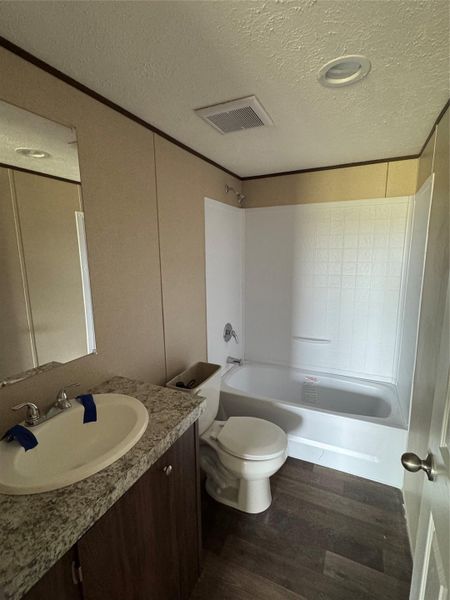 A stone-look countertop vanity complements the dark flooring in this practical bathroom layout.
