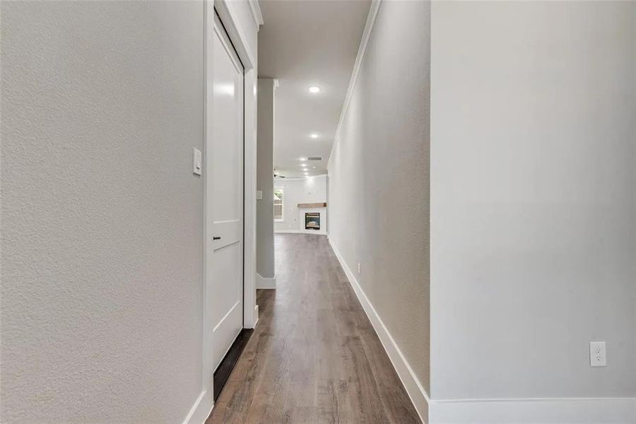 Hallway with a textured wall, dark wood-style flooring, and recessed lighting
