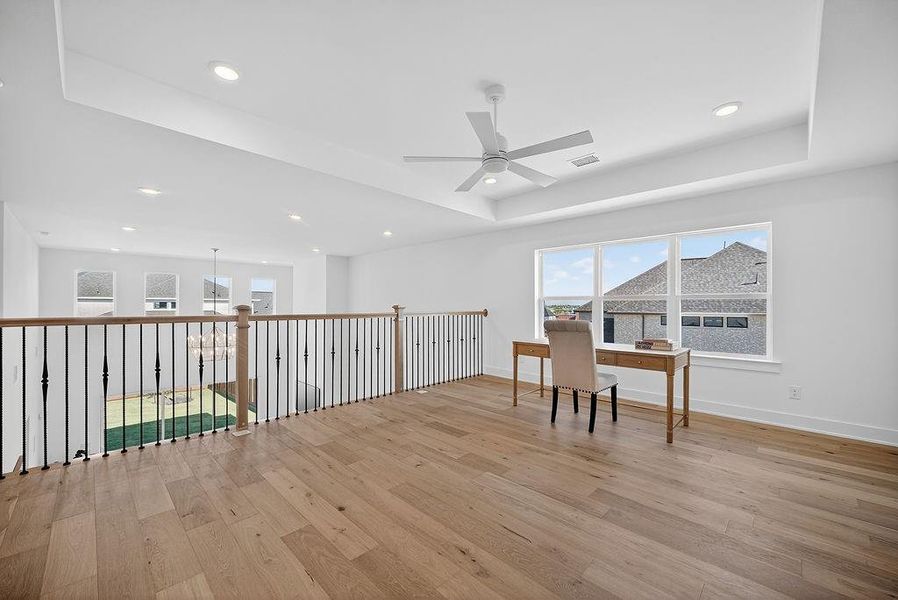 Office area with a raised ceiling, plenty of natural light, light wood finished floors, ceiling fan, and recessed lighting Office area with a raised ceiling, plenty of natural light, light wood finished floors, ceiling fan, and recessed lighting