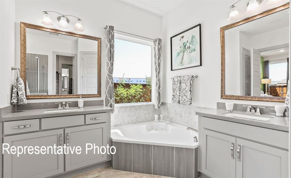 Dual vanity with integrated sinks, light gray cabinetry, and brass-framed mirrors Dual vanity with integrated sinks, light gray cabinetry, and brass-framed mirrors