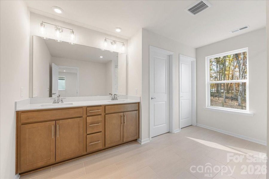 Primary Bath Featuring Stained Wood Cabinetry and Dual Vanity.