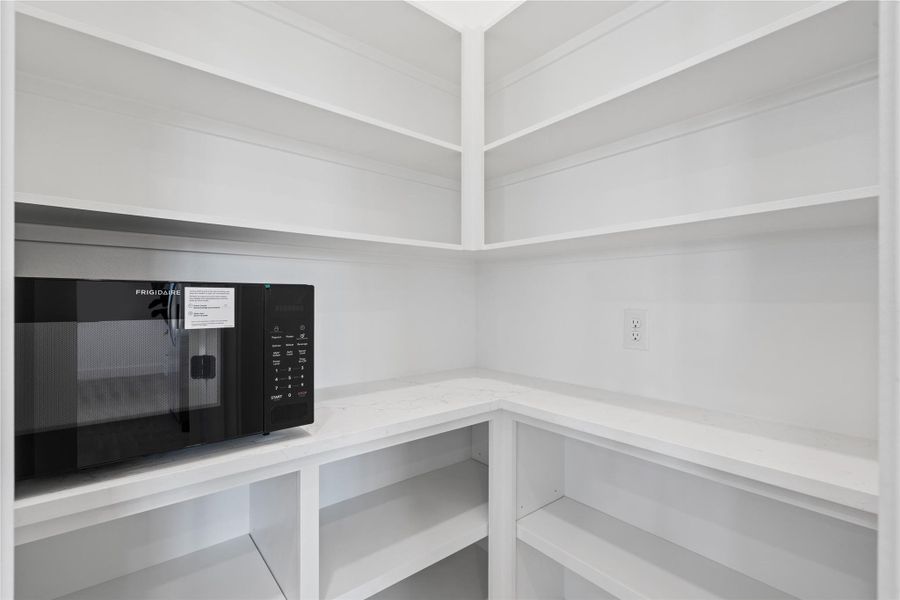 A walk-in pantry designed for clarity and accessibility, featuring wraparound shelving that maximizes storage capacity while keeping the footprint efficient and easy to navigate.