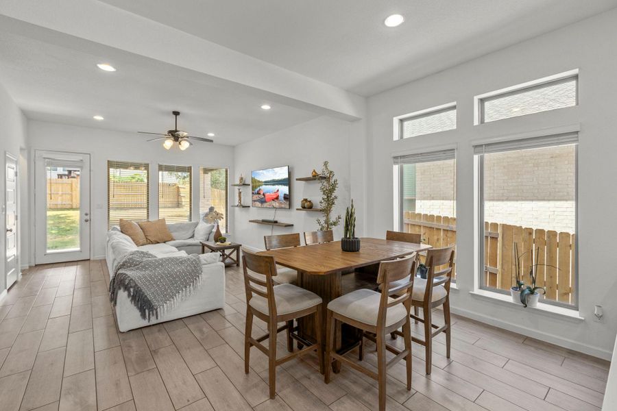 Generous windows frame outdoor views in this open, tile-floored dining and living space.