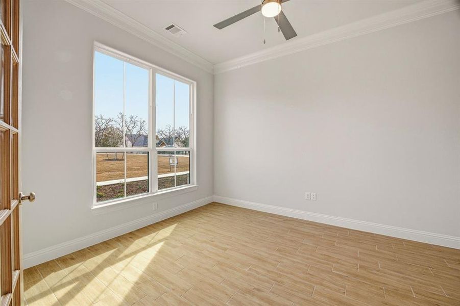 Empty room with light wood-style floors, crown molding, and a ceiling fan Empty room with light wood-style floors, crown molding, and a ceiling fan