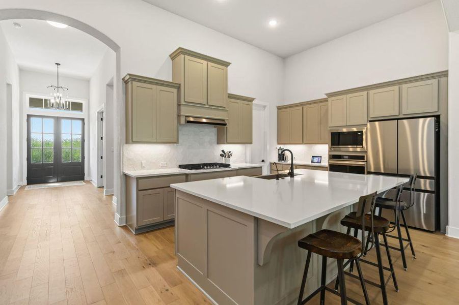 An inviting kitchen with a central island offers seamless flow to the arched entry and front doors.