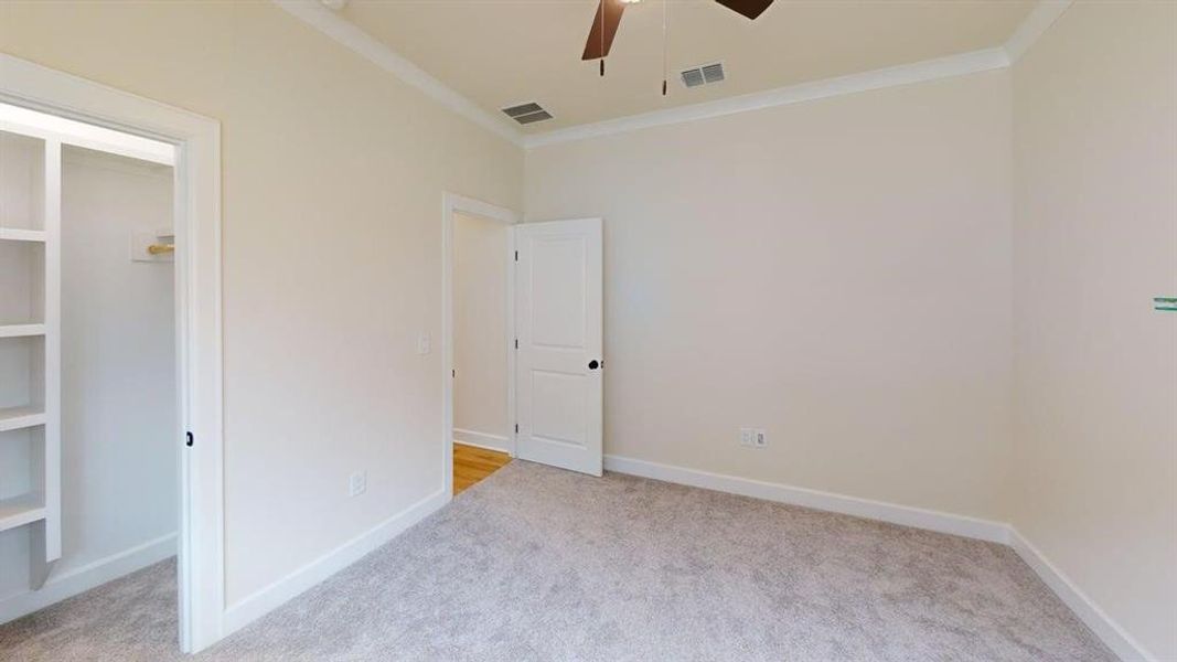 Unfurnished bedroom with carpet floors, ornamental molding, and a ceiling fan