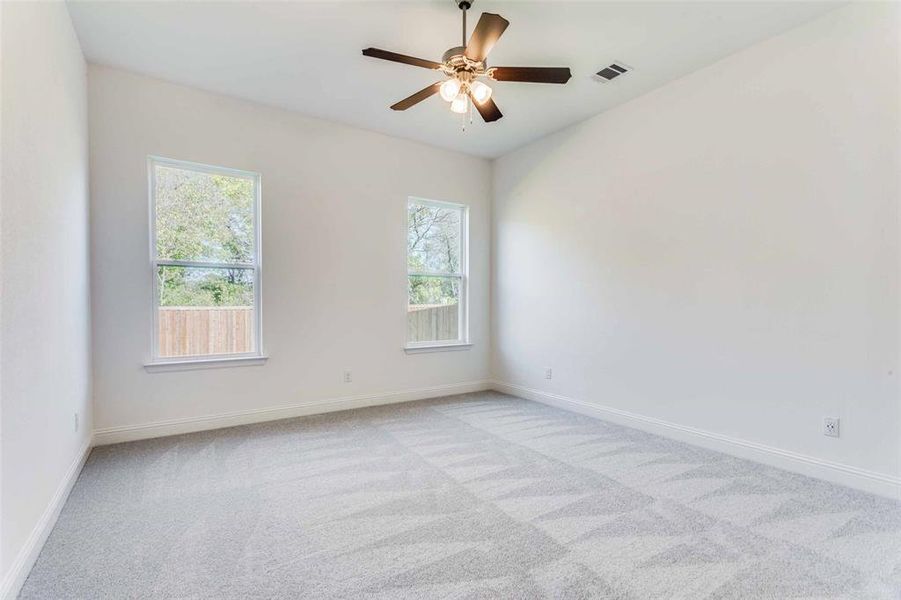 Carpeted empty room with ceiling fan and a healthy amount of sunlight