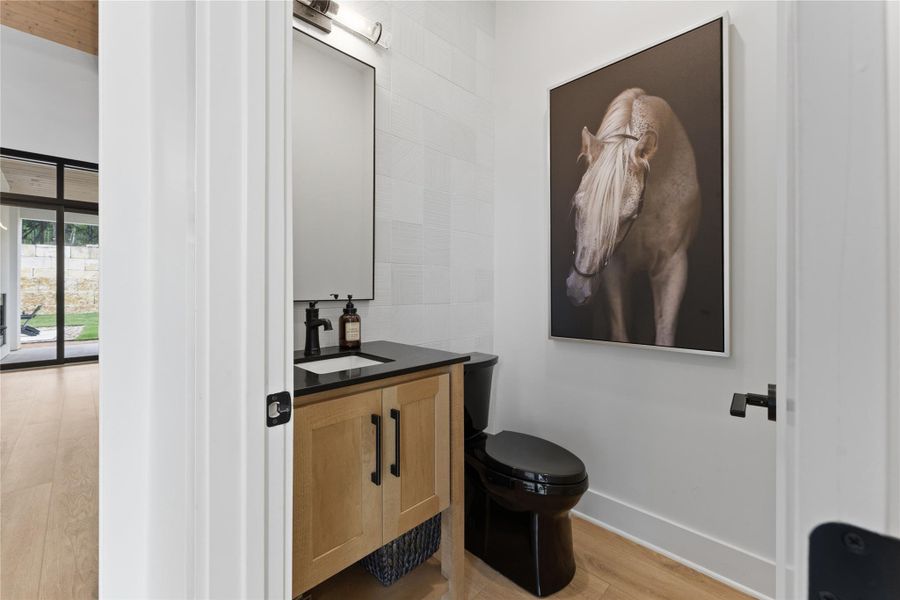 Powder room featuring a wood-finish vanity with black countertop, rectangular undermount sink, and matte black faucet Powder room featuring a wood-finish vanity with black countertop, rectangular undermount sink, and matte black faucet