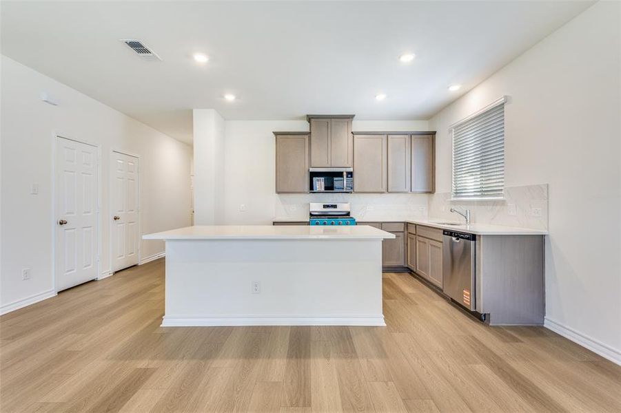 Kitchen featuring a kitchen island, light wood-style floors, recessed lighting, stainless steel appliances, and tasteful backsplash Kitchen featuring a kitchen island, light wood-style floors, recessed lighting, stainless steel appliances, and tasteful backsplash