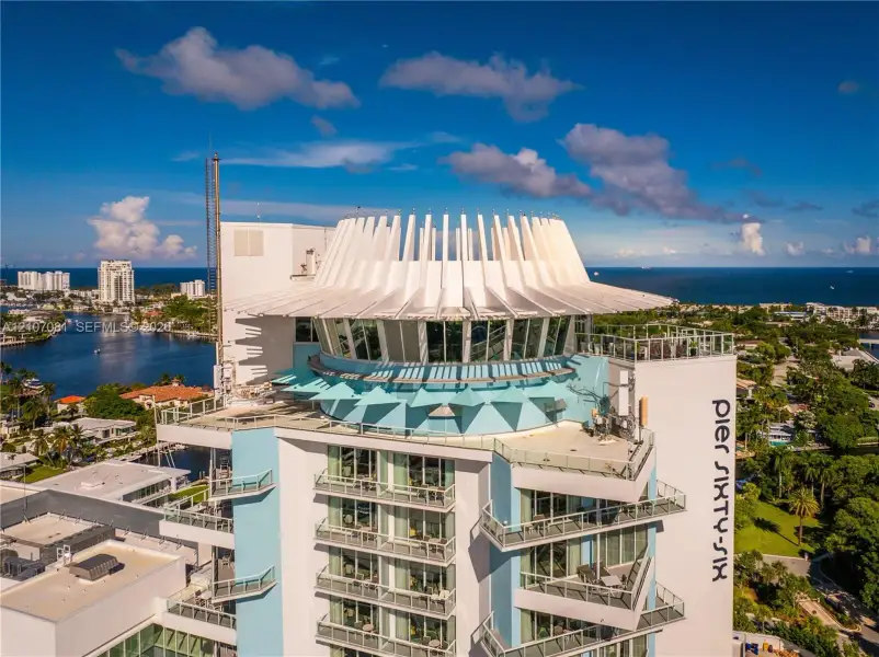 High-rise building featuring a distinctively sculpted crown, expansive floor-to-ceiling glass windows, tiered private balconies, and a reinforced concrete exterior High-rise building featuring a distinctively sculpted crown, expansive floor-to-ceiling glass windows, tiered private balconies, and a reinforced concrete exterior