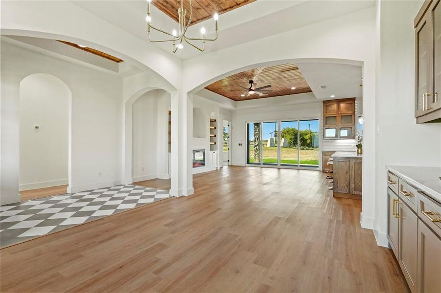 Unfurnished living room featuring light wood-style floors, arched walkways, a chandelier, wooden ceiling, and ceiling fan Unfurnished living room featuring light wood-style floors, arched walkways, a chandelier, wooden ceiling, and ceiling fan