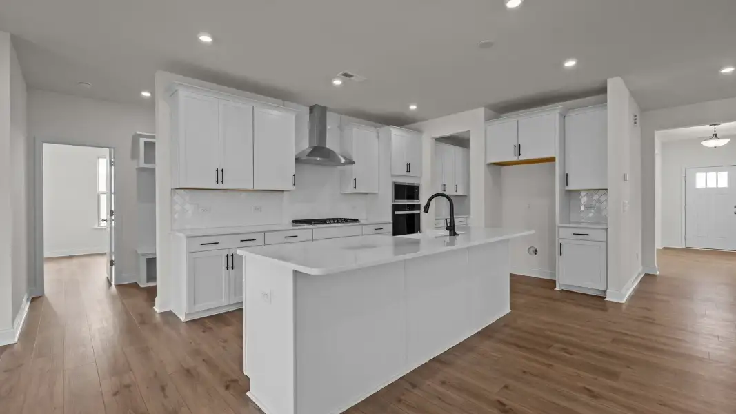 Gourmet Kitchen with premium cabinetry, wall oven, built-in microwave, vented hood, and large island in the Norris Plan Gourmet Kitchen with premium cabinetry, wall oven, built-in microwave, vented hood, and large island in the Norris Plan