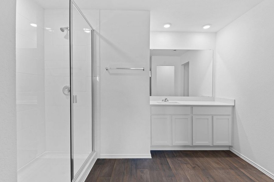 Full bathroom with a shower stall, baseboards, wood finished floors, and vanity