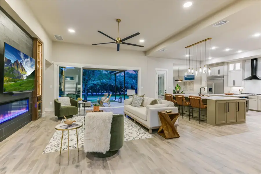 Living room featuring light wood-style flooring, recessed lighting, a ceiling fan, and a fireplace Living room featuring light wood-style flooring, recessed lighting, a ceiling fan, and a fireplace