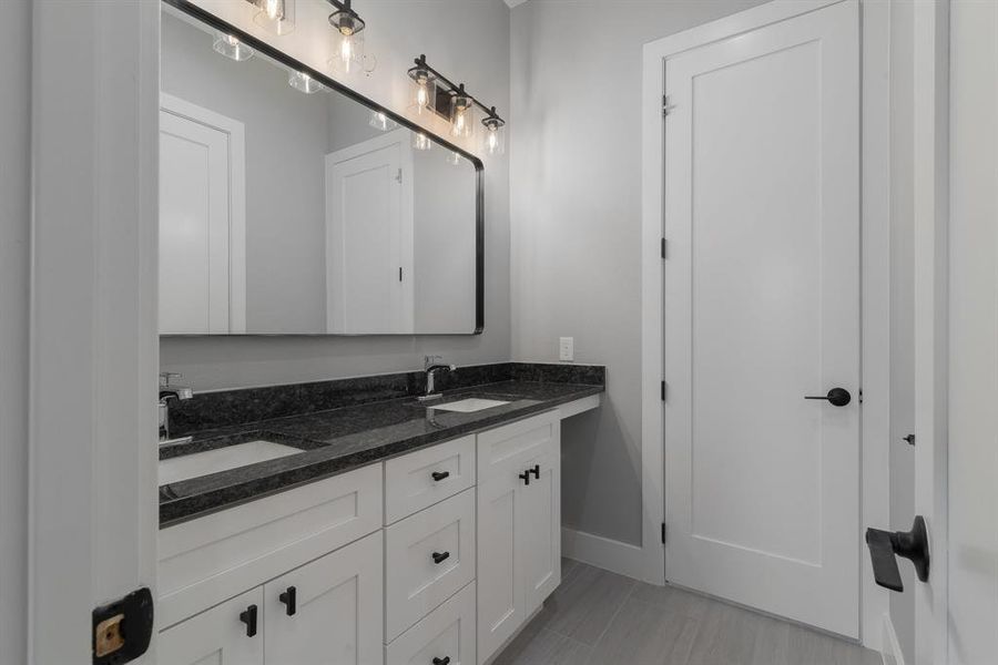 Bathroom featuring double vanity, baseboards, and a sink