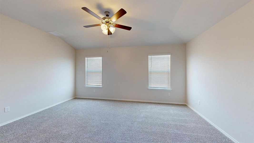 Spacious room featuring vaulted ceilings, light-toned carpeting, two windows with blinds, and a ceiling fan with integrated lighting