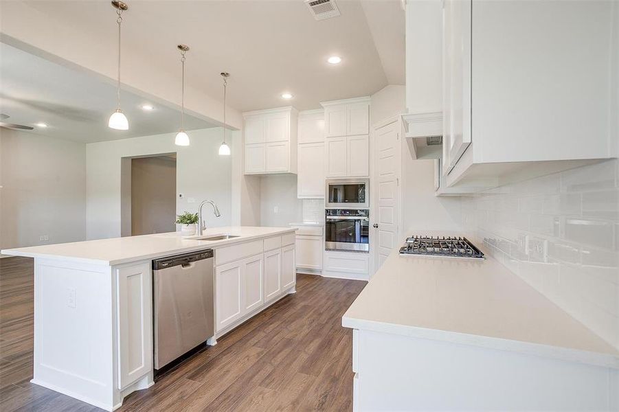 Kitchen featuring sink, white cabinetry, a center island with sink, appliances with stainless steel finishes, and hardwood / wood-style floors