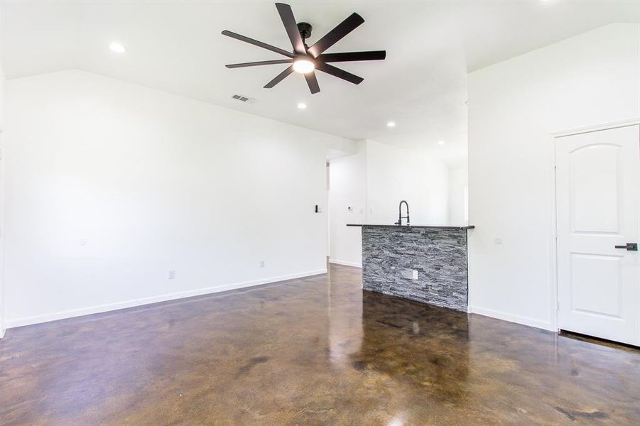 Unfurnished living room featuring vaulted ceiling and ceiling fan