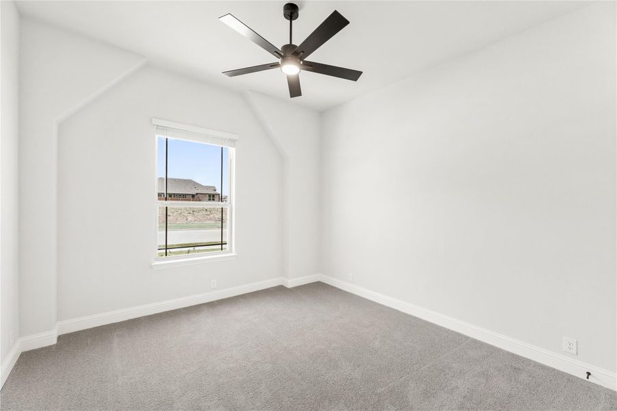 Empty bedroom with vaulted ceiling, black ceiling fan, carpet flooring, and single window Empty bedroom with vaulted ceiling, black ceiling fan, carpet flooring, and single window
