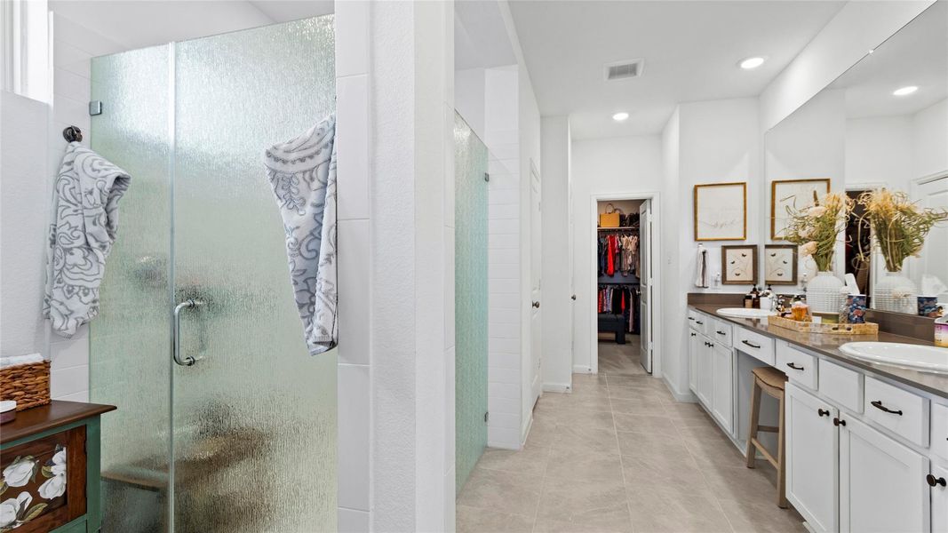 The first full view of the spacious primary bathroom reveals a relaxing, spa-like atmosphere, highlighted by upgraded rain-patterned frosted glass door, shower walls and a thoughtfully designed layout. The first full view of the spacious primary bathroom reveals a relaxing, spa-like atmosphere, highlighted by upgraded rain-patterned frosted glass door, shower walls and a thoughtfully designed layout.