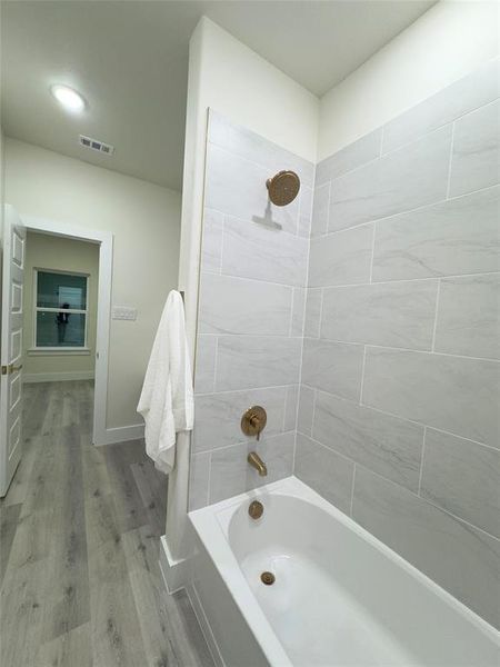 Bathroom featuring tiled shower / bath combo and wood-type flooring