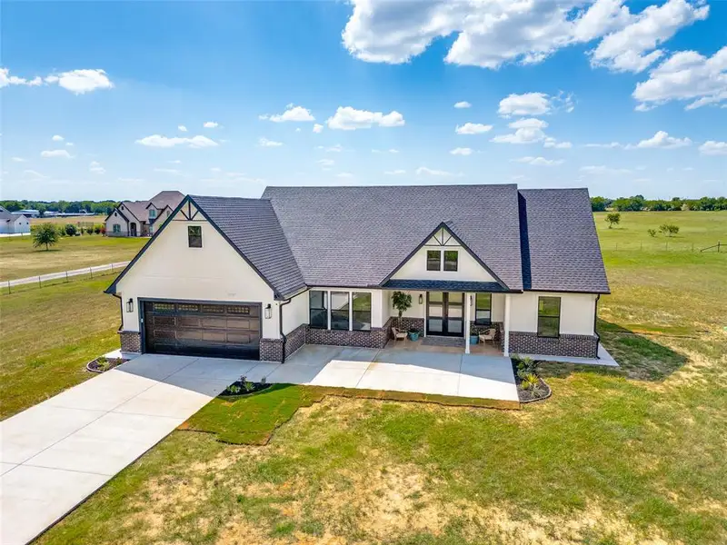 Modern farmhouse-style residence featuring a dark shingle roof, white siding, and dark brick accents