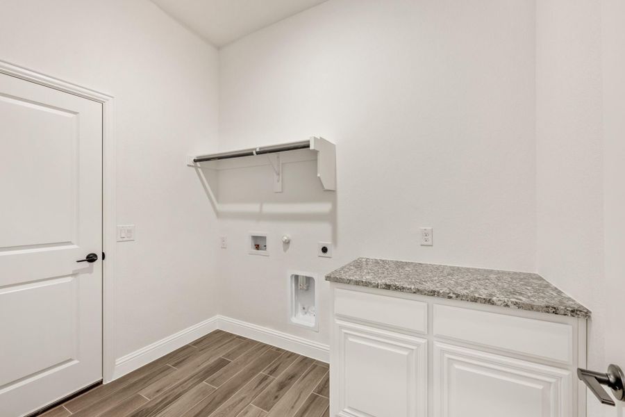Laundry room with white cabinets, granite countertop, wall shelf, and wood-look tile floors Laundry room with white cabinets, granite countertop, wall shelf, and wood-look tile floors
