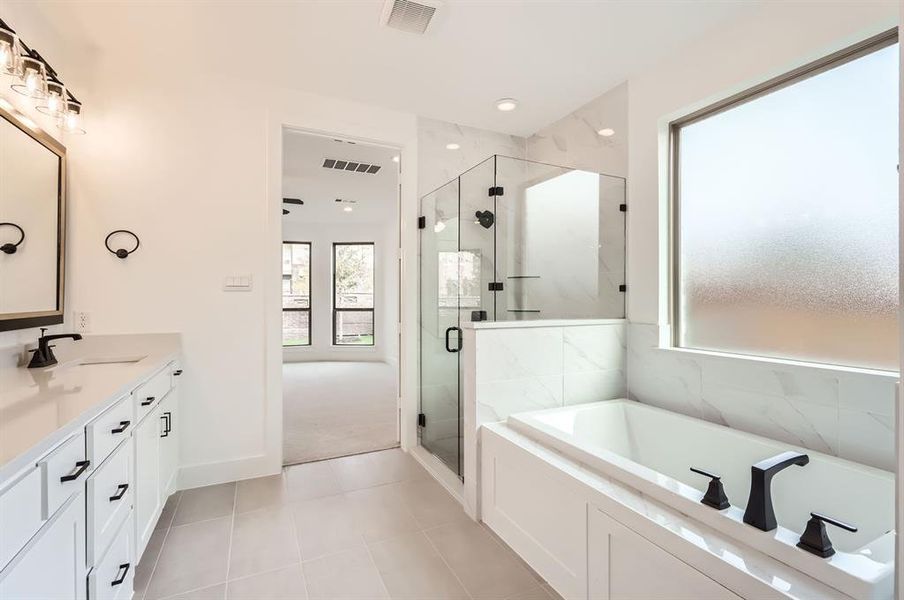 Bathroom featuring plus walk in shower, vanity, and tile patterned flooring